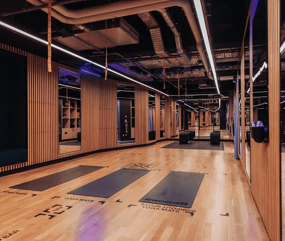 A wooden gym with mirrors and white lights and yoga mats on the floor