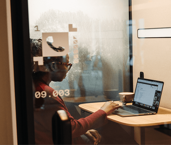 A woman in an individual work pod looking down at her laptop.