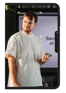 Man in white tshirt stood in front of a screen holding a Ledger signer device framed by a Ledger signer device