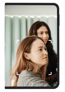 Two women looking in the distance framed by a Ledger signer device