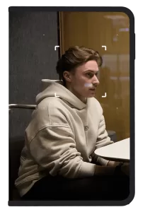 Man in white hoodie sitting in a work pod framed by a Ledger signer device