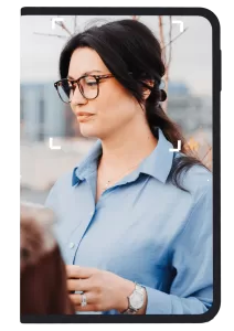 Woman in blue shirt with glasses framed by a Ledger signer device