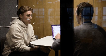 Two men in a work pod having a meeting with only one man's face visible